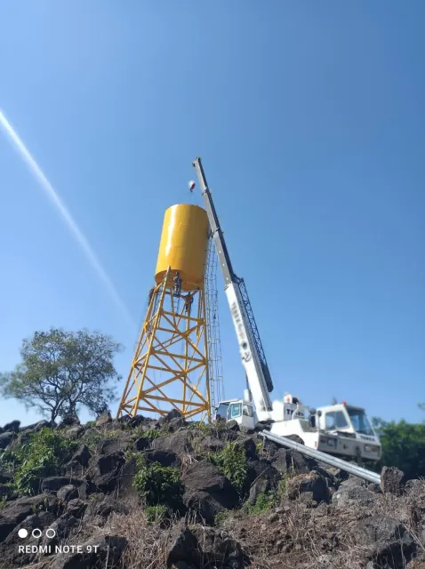 Camión grúa hidráulica izando una carga junto a una estructura