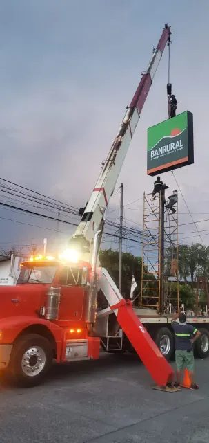 Camión grúa roja con la pluma extendida al atardecer