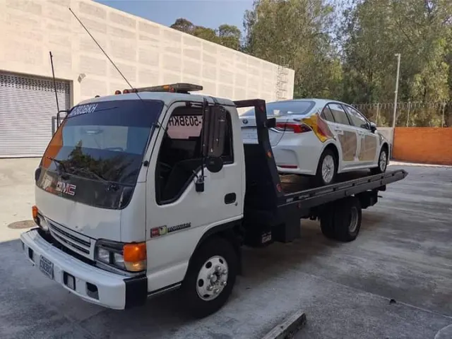 Grúa de plataforma blanca transportando un automóvil