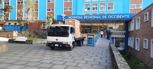 Camión pequeño frente a un edificio hospitalario