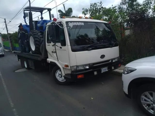 Grúa de plataforma con un tractor azul sobre la plataforma